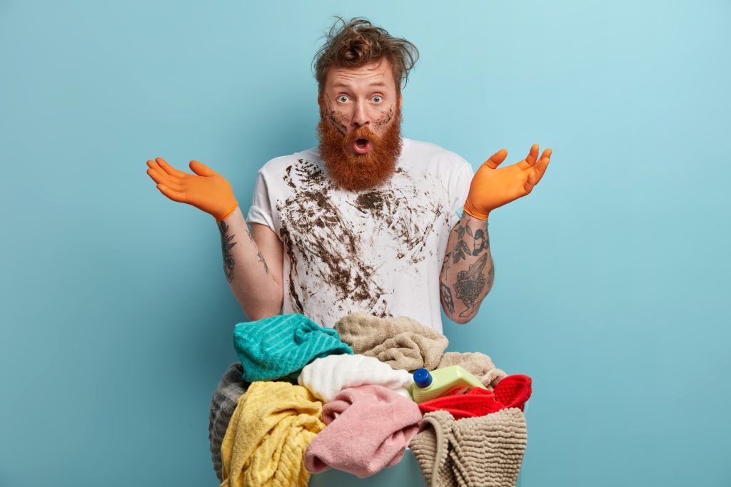 bearded-man-holds-laundry-basket-overwhelmed-by-household-chores