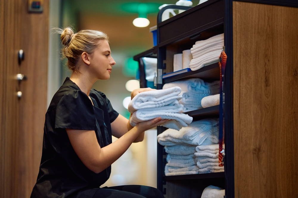 Young,Housekeeper,Taking,Clean,Towels,From,Room,Attendants',Trolley,While