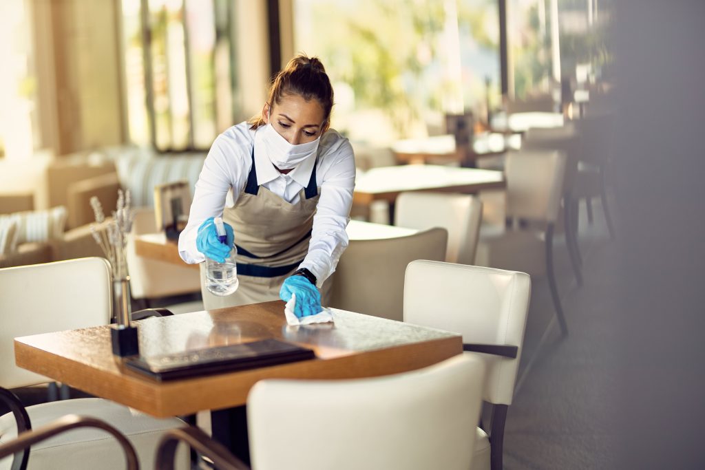 waitress-with-face-mask-disinfecting-restaurant-tables-due-coronavirus-pandemic-min