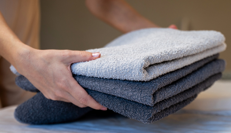 Hands Holding a Stack of Freshly Washed and Folded Gym Towels, Illustrating the Quality Result of ByNext Service