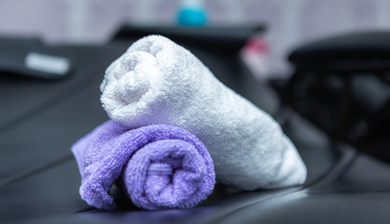 Stack of Freshly Rolled White and Purple Towels, Representing ByNext's Professional Gym Laundry Service