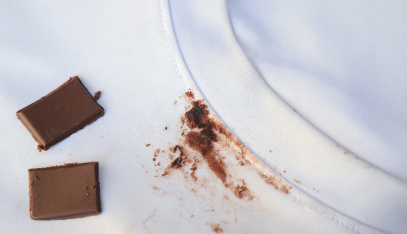 Pieces of Chocolate Next to a Fresh Chocolate Stain on White Fabric, Illustrating the Need for Immediate and Correct Stain Removal