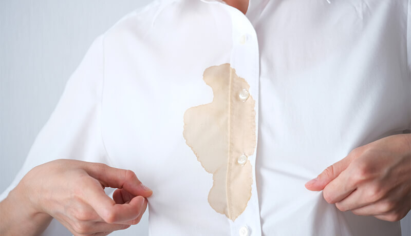 Applying an absorbent cleaning paste to a fresh oil stain on white fabric to prevent it from setting into the fibers before washing.